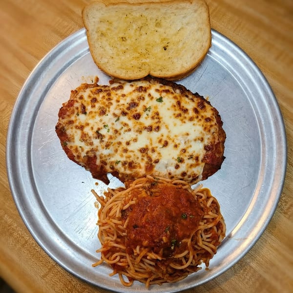 Chicken parmesan with melted cheese, spaghetti with red sauce, and a slice of garlic bread on a metal plate.